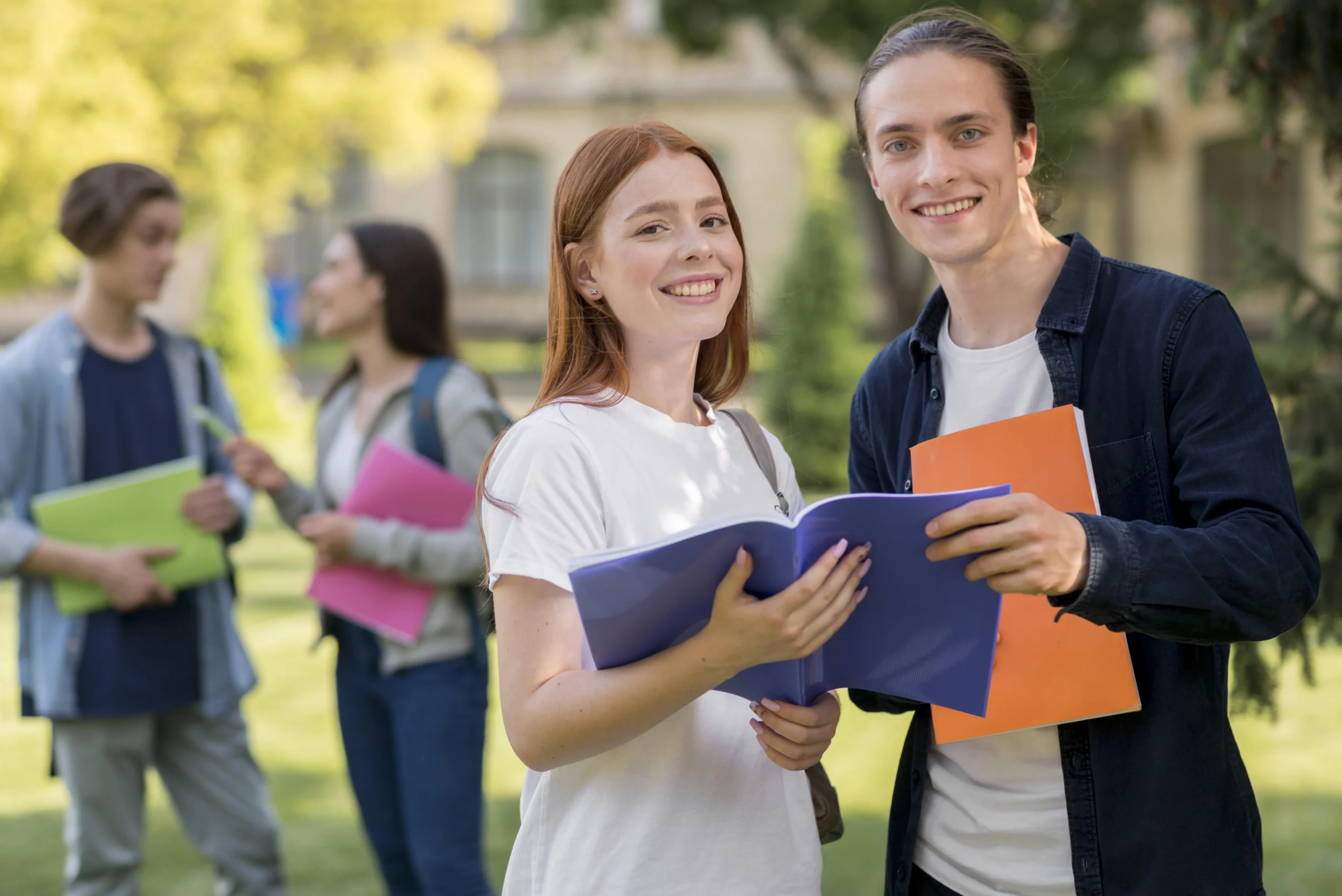 Studenci stojący na terenie uczelni i przeglądający materiały do nauki